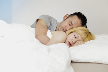 Junges Paar schläft auf einem Bett an der Wand zu Hause - FSIF03150