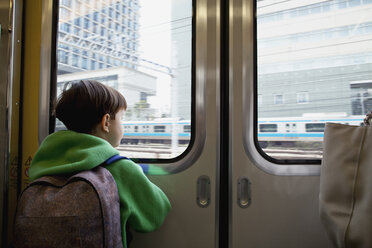 Rear view of boy looking through closed door while traveling in train - FSIF03152