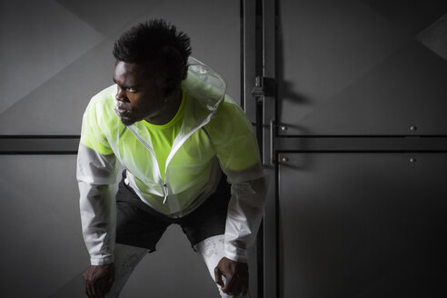 Young man with mohawk, wearing sports clothing, hands on knees - ISF09221