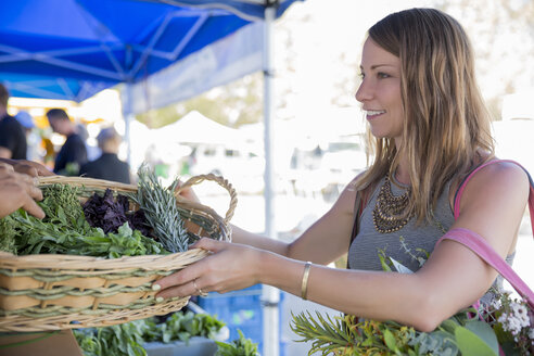 Woman at fruit and vegetable stall receiving basket of fresh herbs - ISF09240