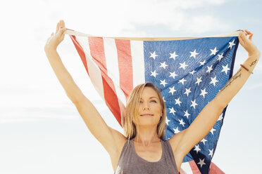 Woman with arms raised holding american flag - ISF09263