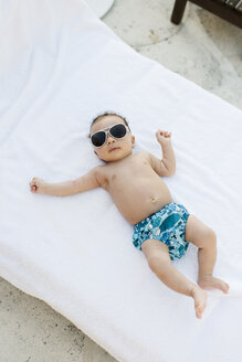 Baby mit Sonnenbrille auf Matratze liegend - ISF09270