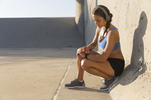 Female athlete with headphones, checking smartwatch - ISF09284