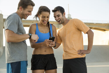 Sportler lachen über eine Nachricht auf dem Mobiltelefon, Van Nuys, Kalifornien, USA - ISF09293