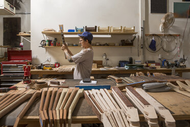 Guitar maker in workshop quality checking guitar neck - ISF09321