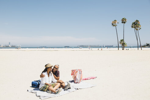 Älteres Paar sitzt auf einer Picknickdecke am Strand, Long Beach, Kalifornien, USA - ISF09328