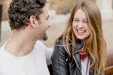 Happy young couple sitting on park bench - CUF23143