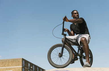 Young man on BMX bicycle looking over his shoulder in skatepark - CUF23164