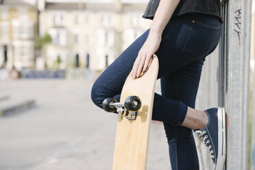 Taille einer Skateboarderin, die sich gegen den Zaun eines Skateparks lehnt - CUF23166