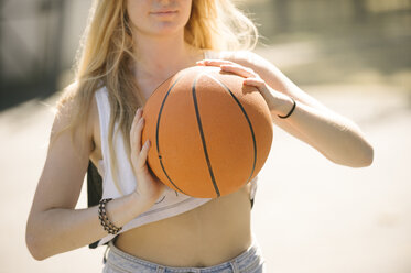 Mittelteil einer jungen Frau beim Üben auf dem Basketballplatz - CUF23177