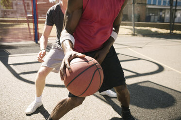 Mid section of two male basketball players practising on basketball court - CUF23181