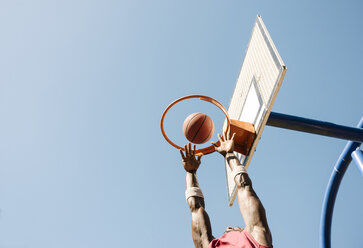 Young male basketball player throwing ball in basketball hoop - CUF23183