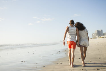 Rückansicht eines romantischen jungen Paares, das am Strand spazieren geht, Kapstadt, Westkap, Südafrika - CUF23196