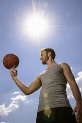 Junger männlicher Basketballspieler balanciert und dreht den Ball auf dem Finger - CUF23267