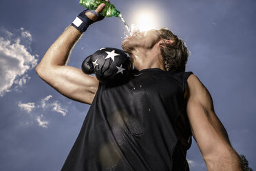 Low angle view of mid adult male boxer drinking bottled water - CUF23272