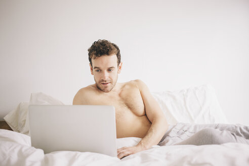 Junger Mann im Bett liegend mit Laptop - CUF23315