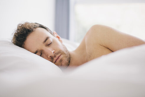 Young man lying on side asleep in bed - CUF23321