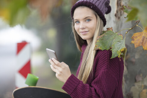 Porträt eines lächelnden Teenagers mit Handy und Skateboard - ZEF15596