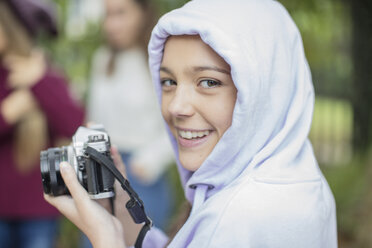 Portrait of smiling teenage girl with camera outdoors - ZEF15607