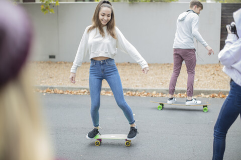 Glückliche Teenager-Freunde fahren auf der Straße Skateboard, lizenzfreies Stockfoto