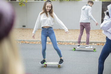 Glückliche Teenager-Freunde fahren auf der Straße Skateboard - ZEF15608