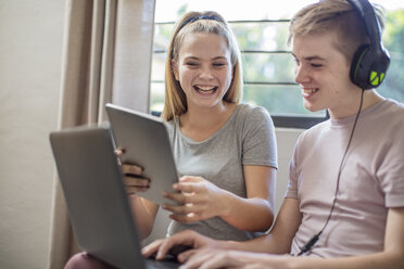 Happy boy and teenage girl with tablet, laptop and headphones - ZEF15628