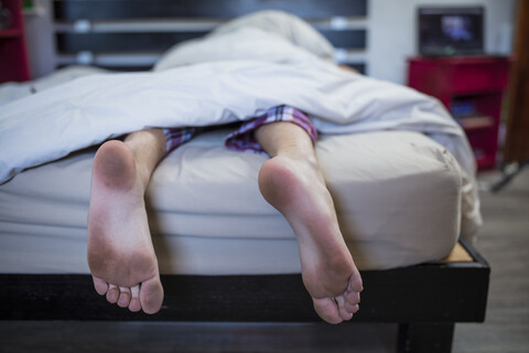 Dirty feet of boy lying in bed stock photo