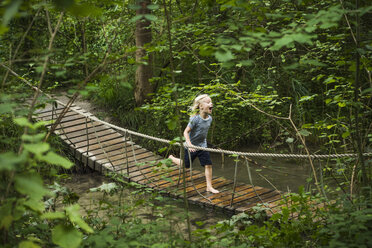 Junge läuft über Fußgänger-Seilbrücke im Wald - CUF23338