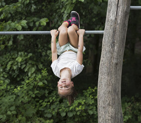 Girl hanging upside down from monkey bar - CUF23361