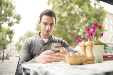 Man at pavement cafe looking at smartphone - CUF23392