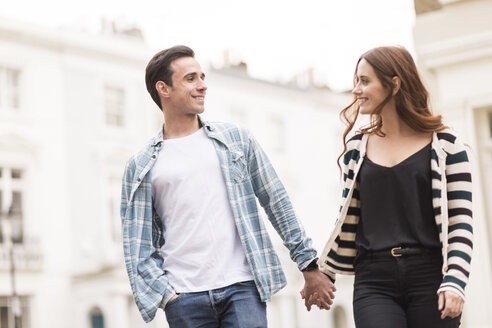 Couple walking in street face to face smiling - CUF23402