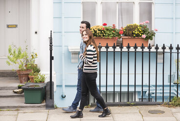 Side view of couple walking in street smiling - CUF23403