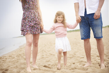 Familie hält sich an den Händen und geht am Strand spazieren - CUF23416