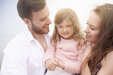 Happy parents carrying daughter in arms - CUF23417