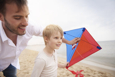 Father and son playing kite on beach - CUF23419
