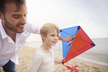 Vater und Sohn spielen Drachen am Strand - CUF23419