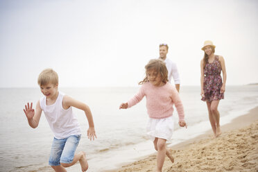 Familie läuft am Sandstrand entlang - CUF23423