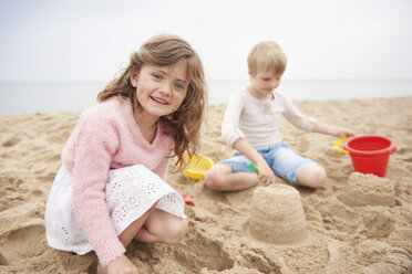 Children building sand castle on beach - CUF23426