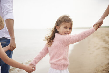 Familie hält sich an den Händen und geht am Strand spazieren - CUF23428