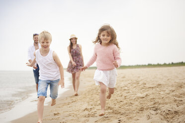 Family running along sandy beach - CUF23429