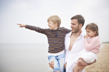 Father carrying children in arms on beach - CUF23431