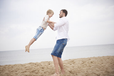 Father swinging son on beach - CUF23434