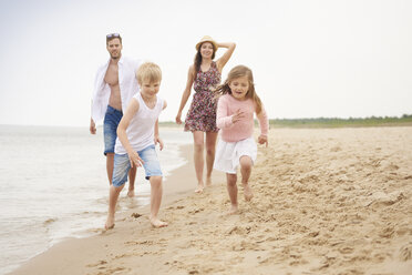 Family running along sandy beach - CUF23436