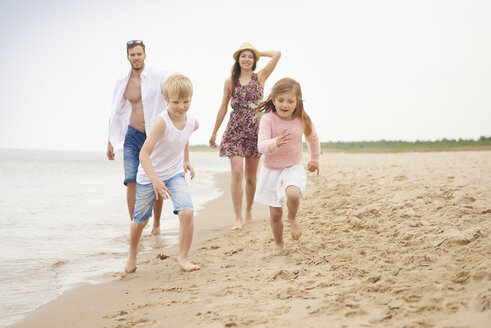 Familie läuft am Sandstrand entlang - CUF23436