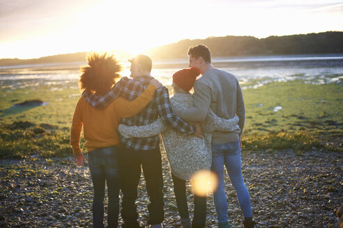 Rückansicht von vier erwachsenen Freunden bei Sonnenuntergang über dem Meer - CUF23441