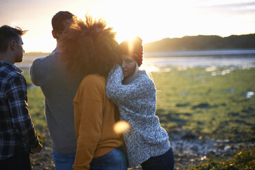 Portrait of young woman with adult friends watching sunset over sea - CUF23442