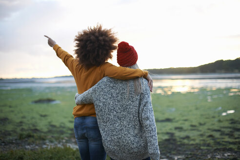 Rückansicht von zwei jungen Frauen am Meer bei Sonnenuntergang - CUF23448