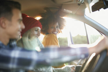 Drei junge erwachsene Freunde in einem Auto im Sonnenlicht - CUF23449