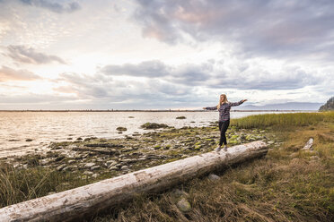 Frau balanciert auf einem Baumstamm am Wreck Beach, Vancouver, Kanada - CUF23450