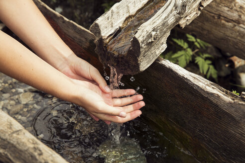 Female hands under fresh running trough water, Sattelbergalm, Tyrol, Austria - CUF23462